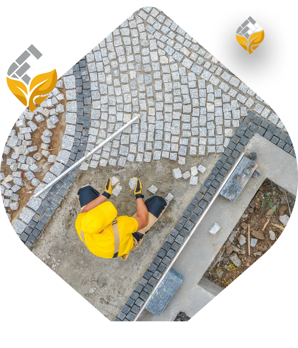 Układanie kostki brukowej na podjeździe przez pracownika w żółtej koszulce