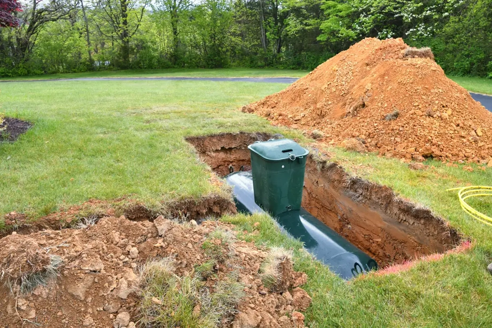 Instalacja szamba w wykopie z widocznym zbiornikiem i hałdą ziemi