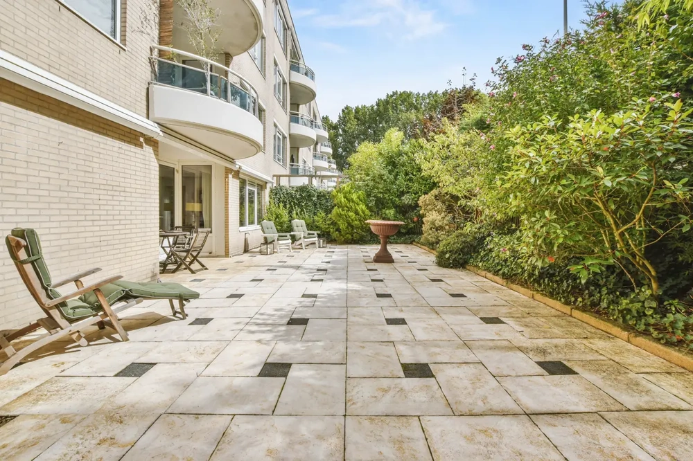 Płyty tarasowe betonowe na dużym patio przy budynku, z krzewami i meblami ogrodowymi