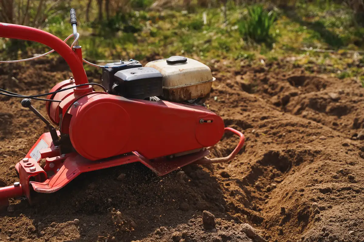 Czerwona glebogryzarka wykonująca usługi glebogryzarką przy przygotowaniu terenu
