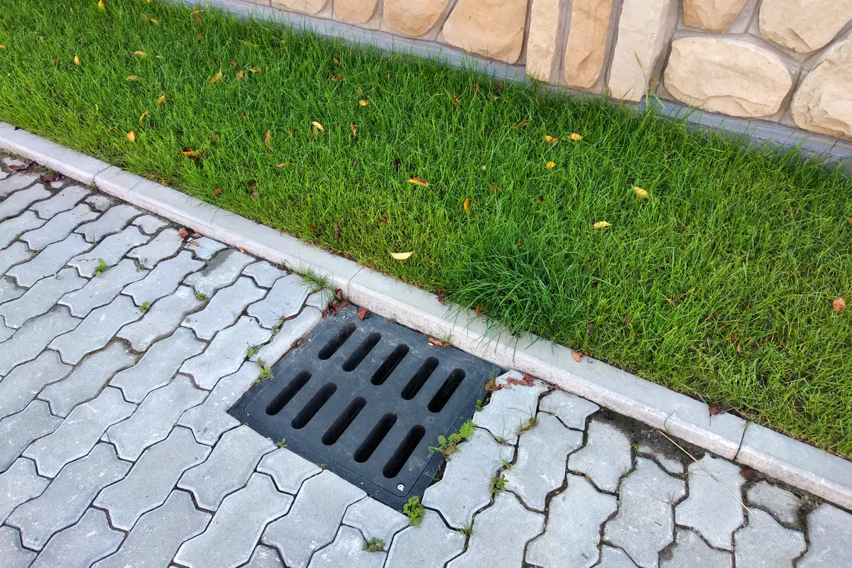 Układanie kostki brukowej z krawężnikami i odwodnieniem liniowym przy trawniku