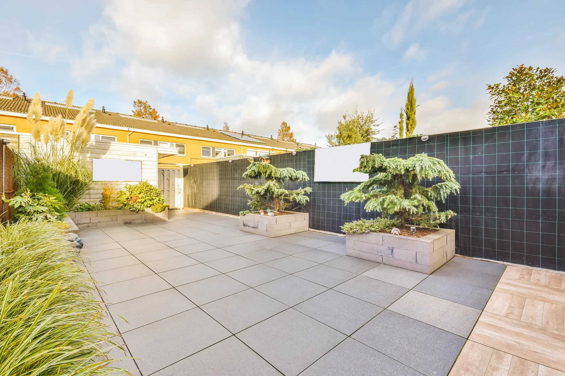 Płyty tarasowe betonowe ułożone na patio z donicami i roślinami ozdobnymi